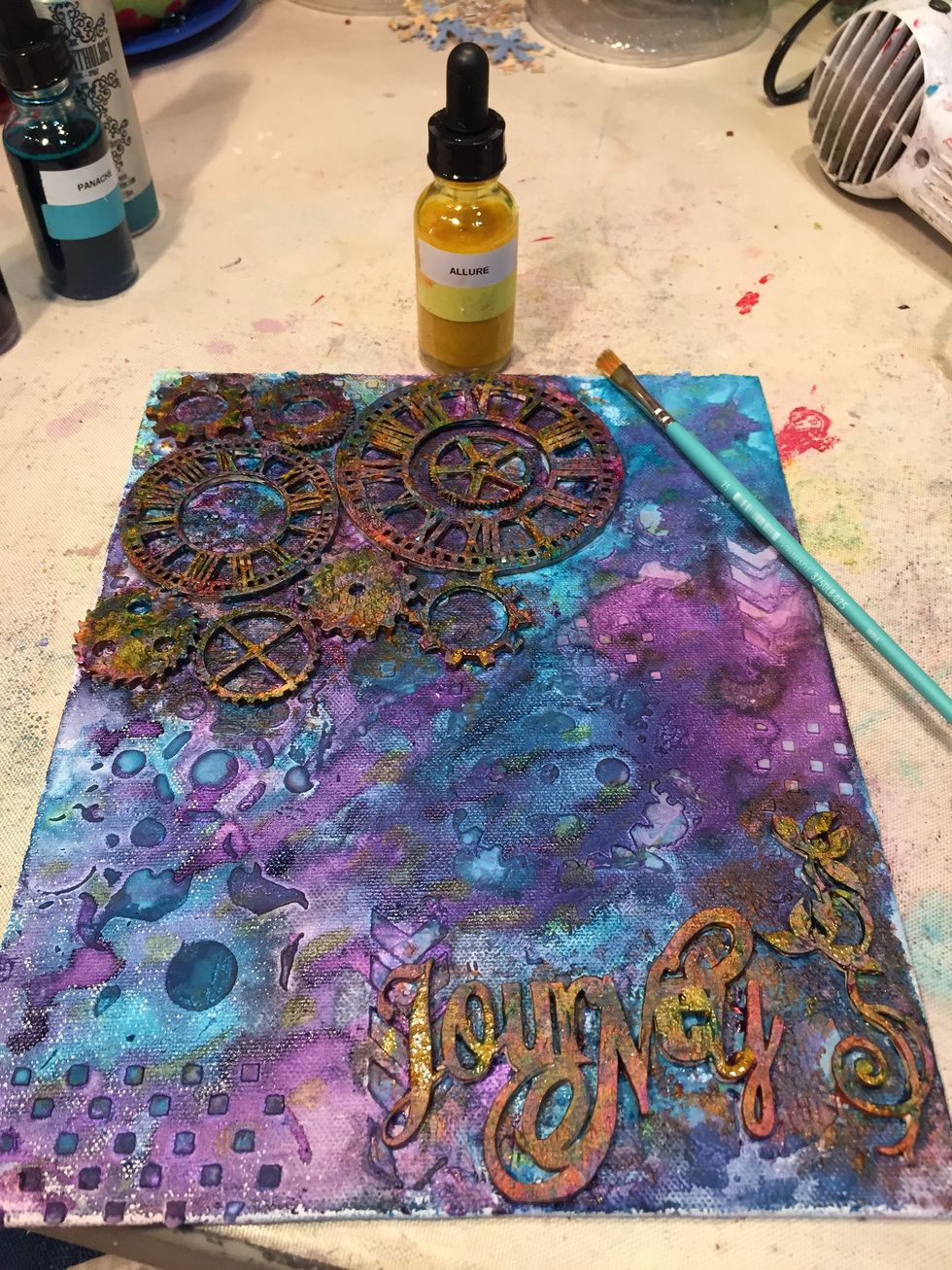 Next, squeeze out some Allure Minx onto your craft mat and dab it on various places, including the canvas itself, with a small paintbrush. This lightens the wooden pieces and adds a nice shimmer.