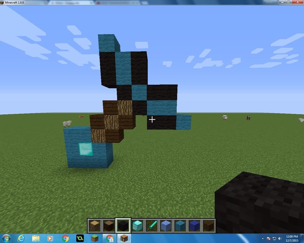 Next take 2 more Cyan Wool Blocks and add them on the sides. Also get 8 more Black Wool Blocks and add them on to the same places as in the picture.