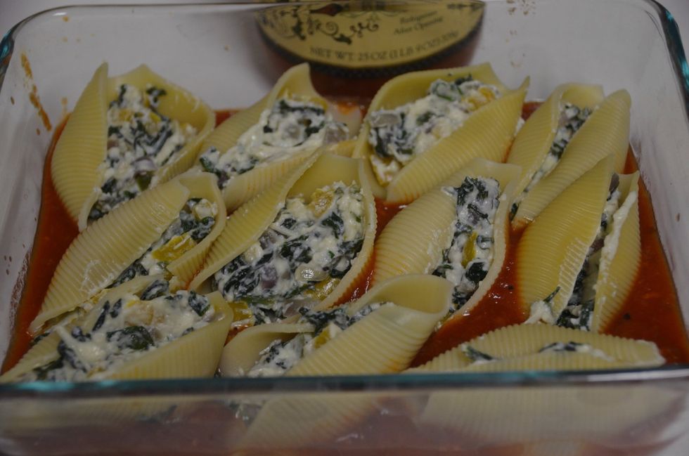 Next take cooked pasta shells and stuff them with the spinach ricotta stuffing and arrange them on the baking dish.