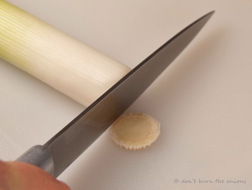 Next take leek and chop of its woody stem.