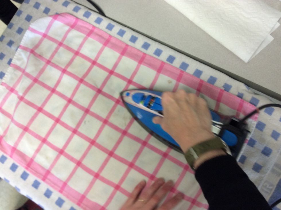 Next take the iron and rub it in on top of the thin towel.