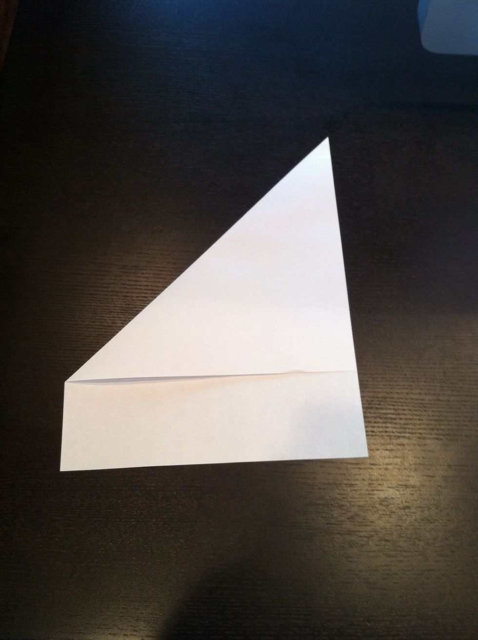 Next take the top left corner of the paper and fold it to the right side of the paper. Make sure that it looks like you have a triangle on top of a small rectangle.