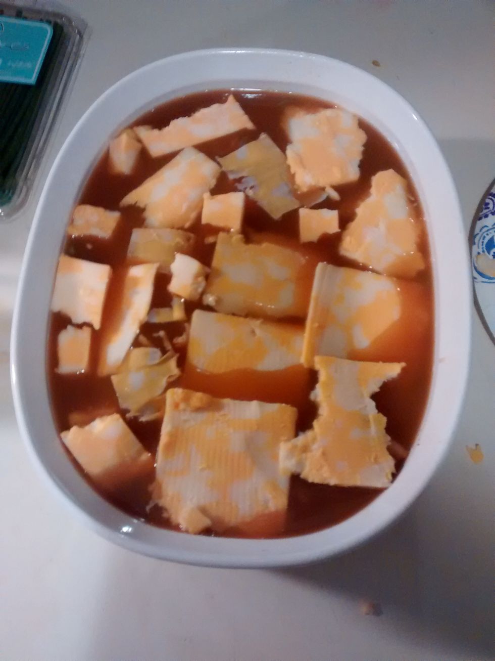 Next take your soup and pour that into the dish. Then take your cheese and place on top of the soup and place it everywhere on the top.