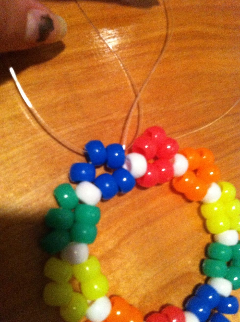 Next thread the string coming out of the white bead into the next 2 blue beads so its coming out of the middle bead.