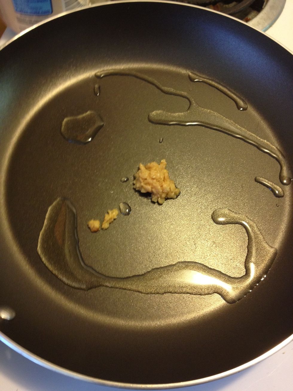 Next, turn on stove to medium heat and drizzle olive oil into pan, then add minced garlic.
