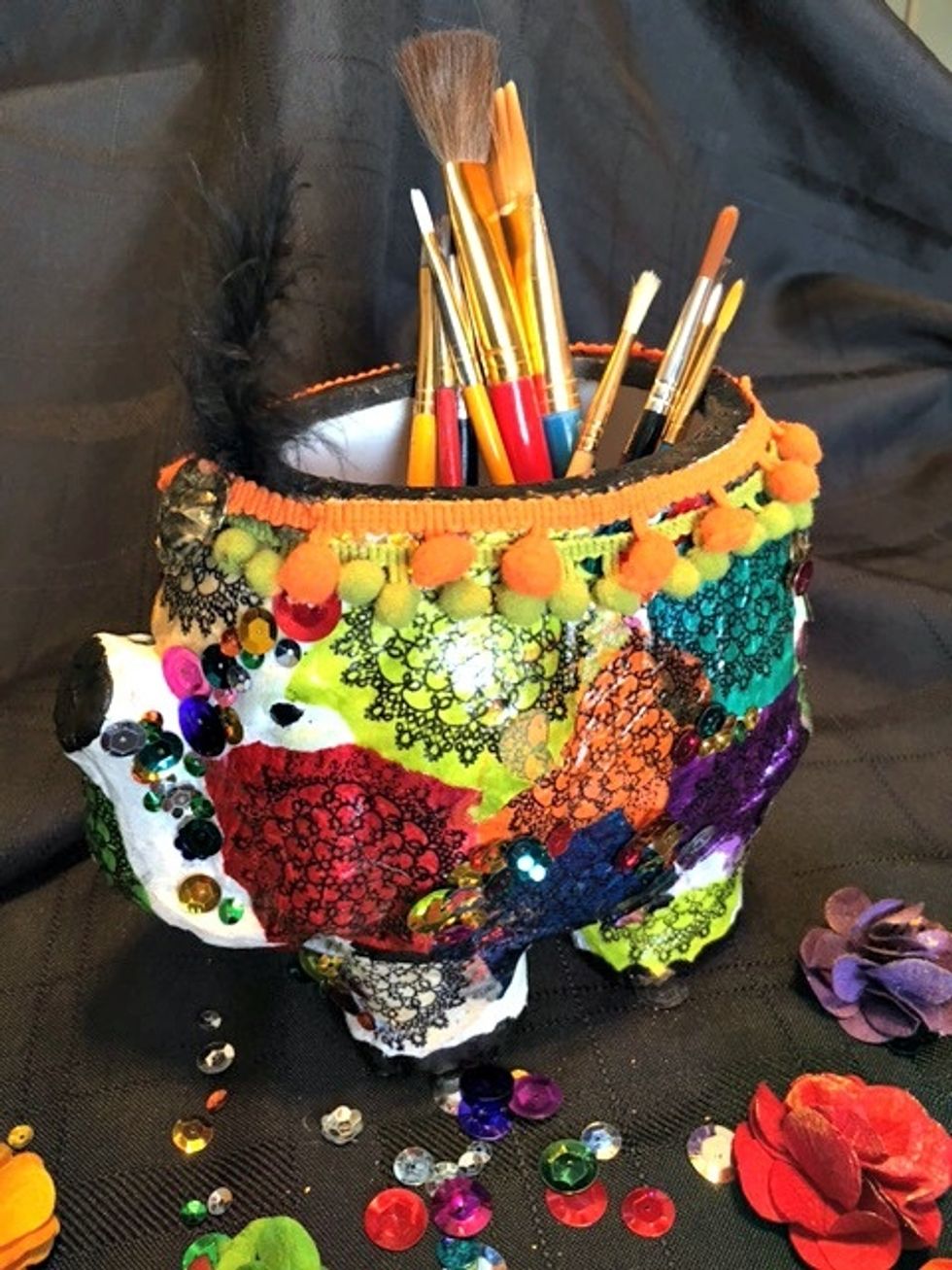 Next up I added some random trim to the top of the container and painted my little elephants eyes with black acrylic paint. And added a feather for his headress...