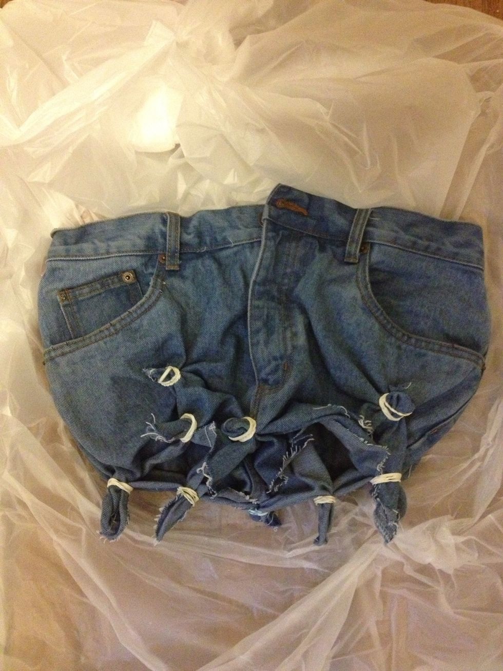 Next, use your rubber bands to tie up your jeans. Rubber band the bottom of the shorts as well as a couple of spots on the front and back of the jeans where you would like that tie dye effect.