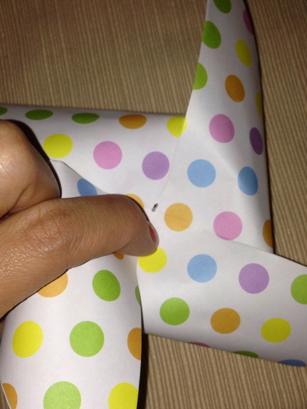 Next, with all 4 corners in place on the pushpin, poke through the center of the paper and through the back. Try twisting the pin around a little, to enlarge the hole just a bit, for better spinning.