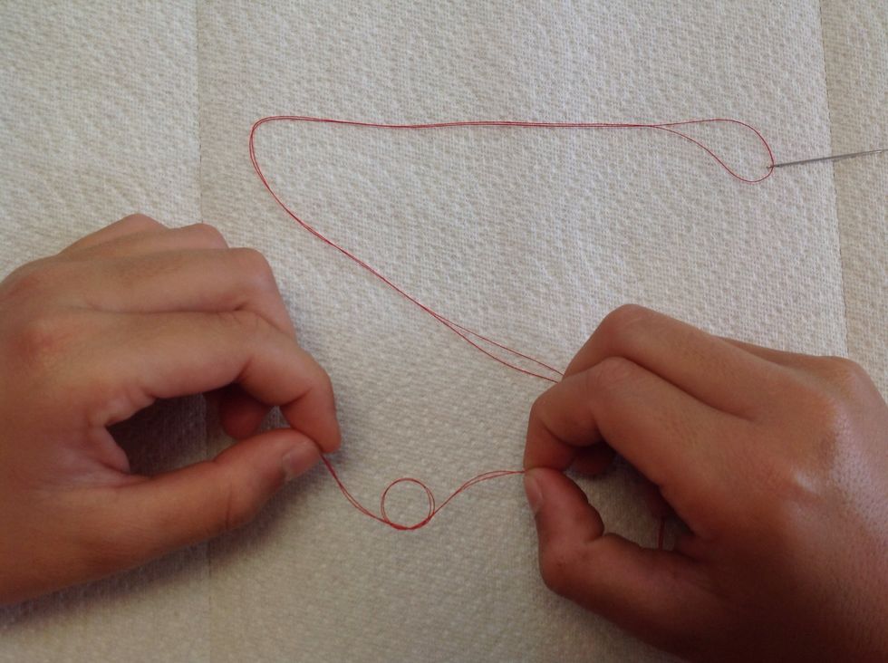 Next, with both ends together, tie a knot to close the open threads.