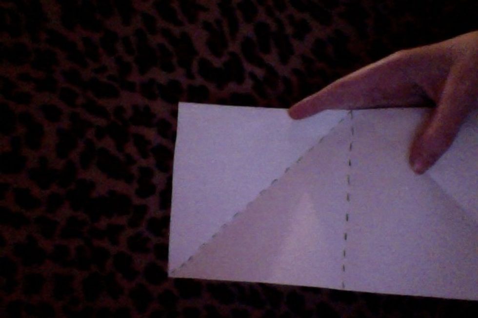 Next, you need to fold one corner of your paper down to meet the center crease.