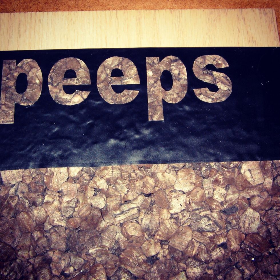 Next you place the adhesive side of the stencil onto the cork. Line it up then rub into the cork. If there are any bubbles along the edges the paint will seep & the finished design will look messy.