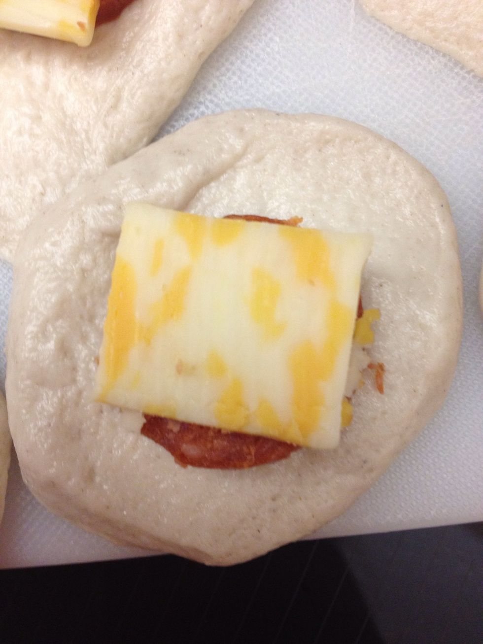 Next you put a slice of the Boar's Head pepperoni and a slice of any cheese and stack them on top of each other on the biscuit.