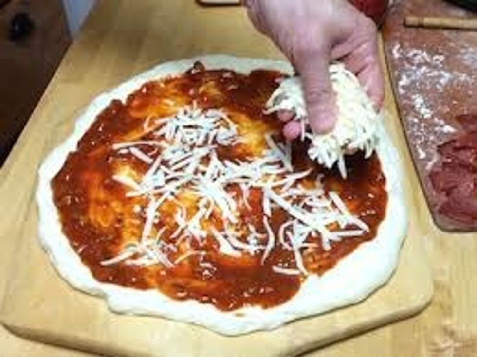 Next you put mozzarella cheese on the pizza and try getting it around the whole pizza!