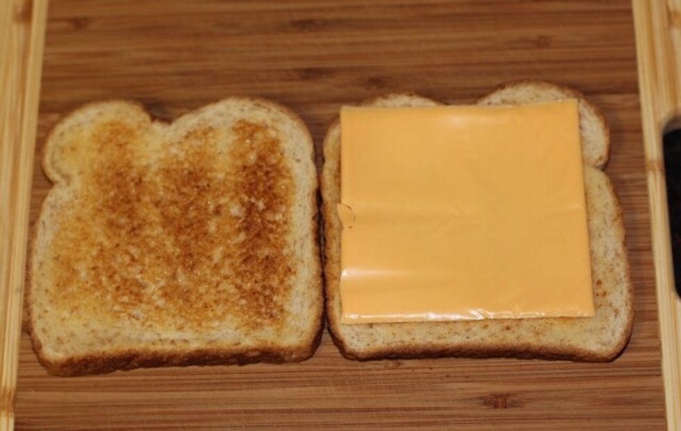 Next you put your slice of cheese on one piece of bread, then you put the other slice of bread on top