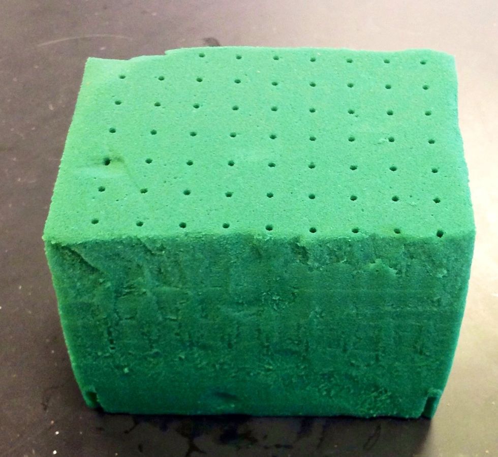 Next you take a 1/3 piece of oasis. It is used as the starting point in arrangements and is used to support the arrangement. Before it is put into the standard dish, it is fully submerged in water.