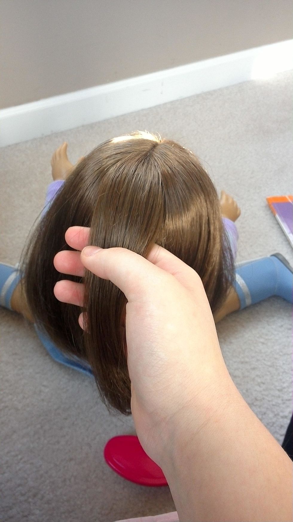 Next, you will want to grab a small section of hair at the center back of her part. Smooth it out with your brush.