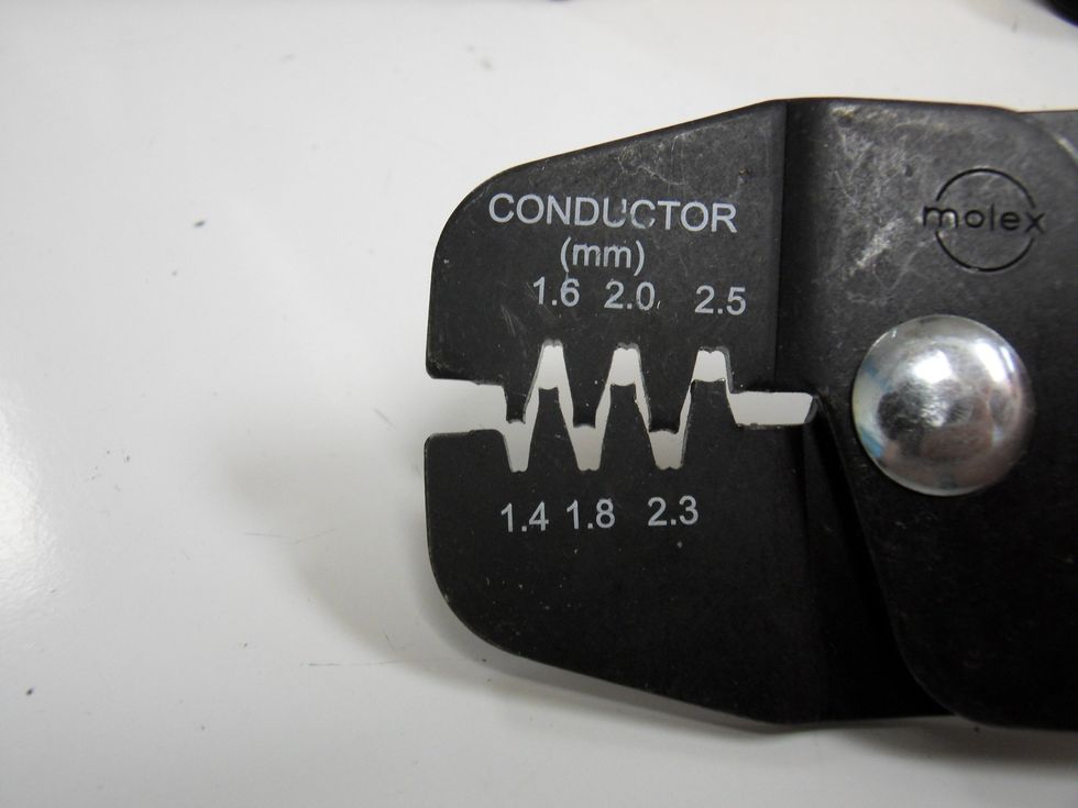 Notice the m-shaped top and u-shaped bottom of each space in the crimper. The opening of the metal socket will line up with the m shape in the crimper.