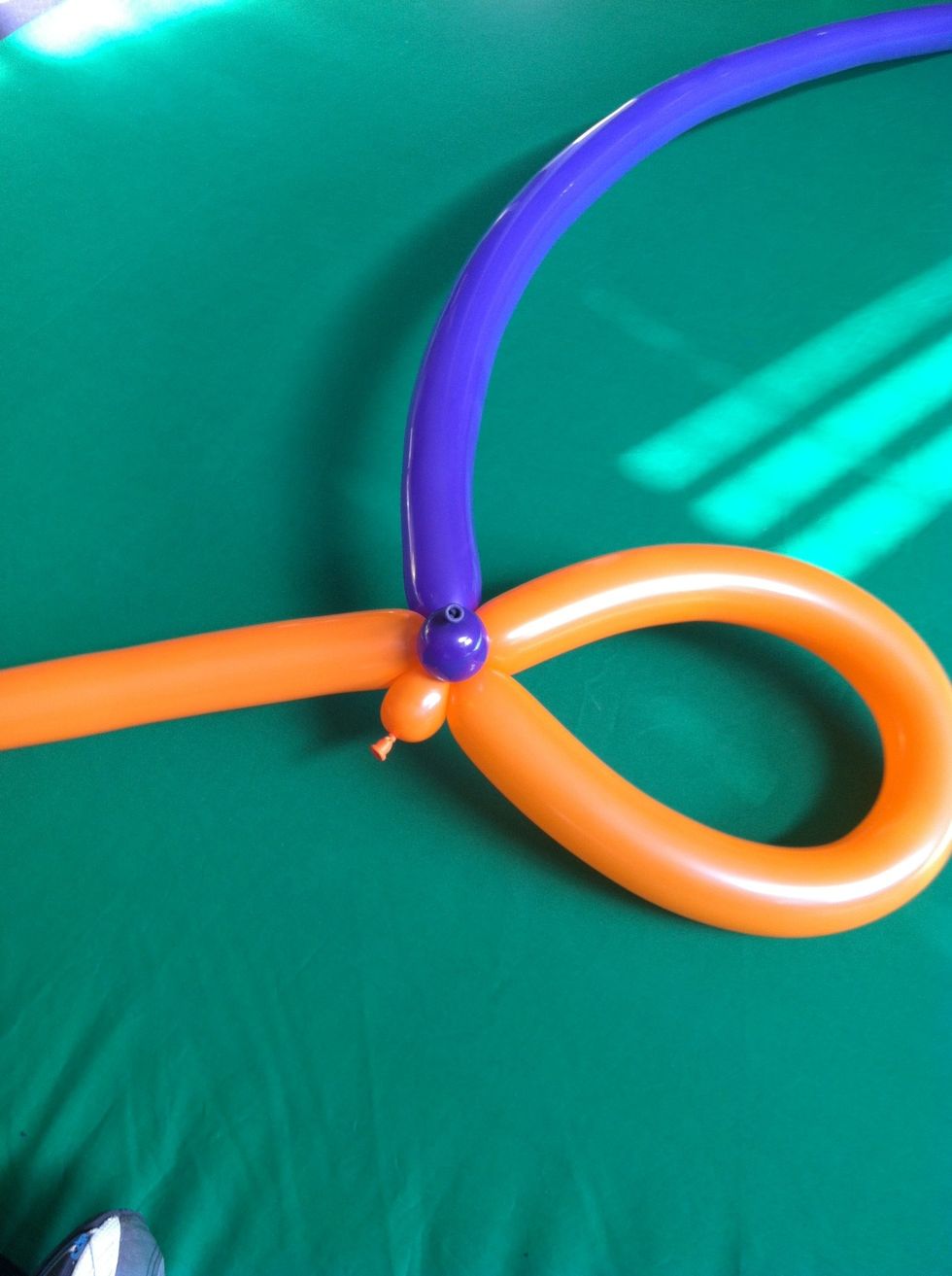 Now add a second balloon to the stick by twisting a small bubble at the base of the new balloon and attaching to the bubble at the base of the hat