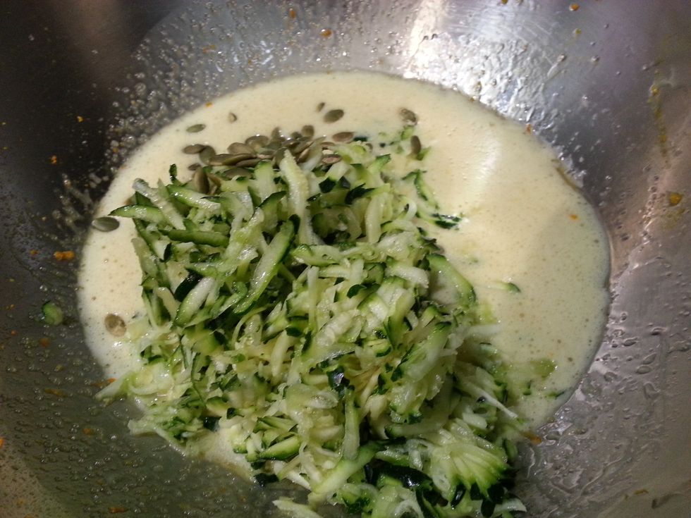 Now add the grated zucchini and pepita. Stir carefully with a spatula. Be careful not to stir vigorously as you don't want to loose the aeration.