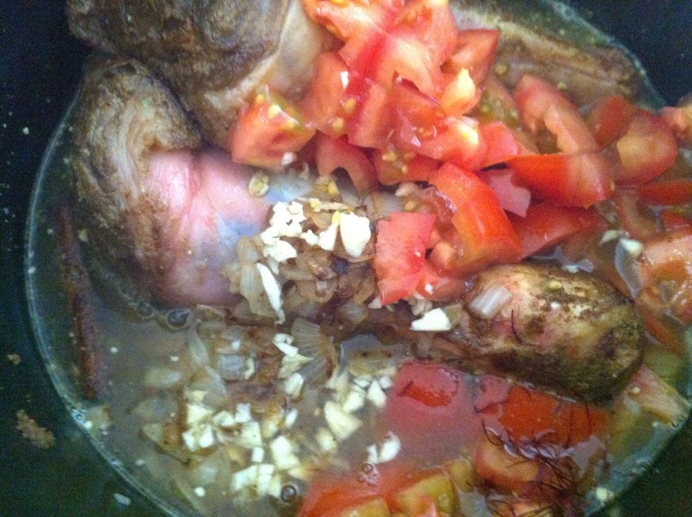 Now add the hot stock,minced garlic and tomatoes to the lamb.I have set the slow cooker to auto setting.