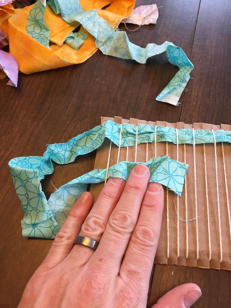 Now begin weaving back the other way, taking care to go UNDER the first warp string and working your way across to the end. Take care to be sure you're going OVER the strings you went UNDER last row.