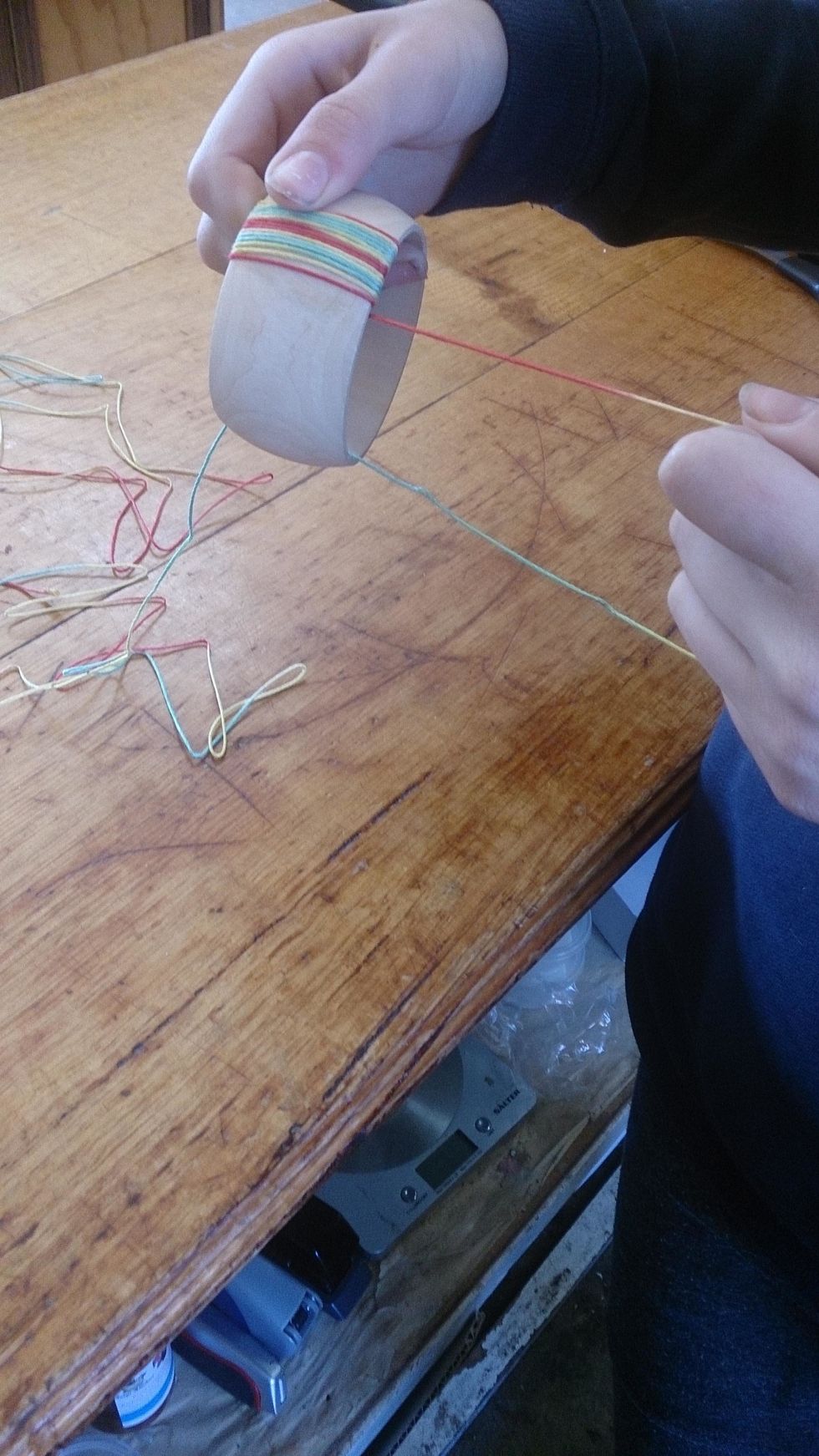 Now, begin wrapping the thread around the bangle. My daughter held the end of the thread with her finger so it could dry. As you go along, squish the threads together tightly.