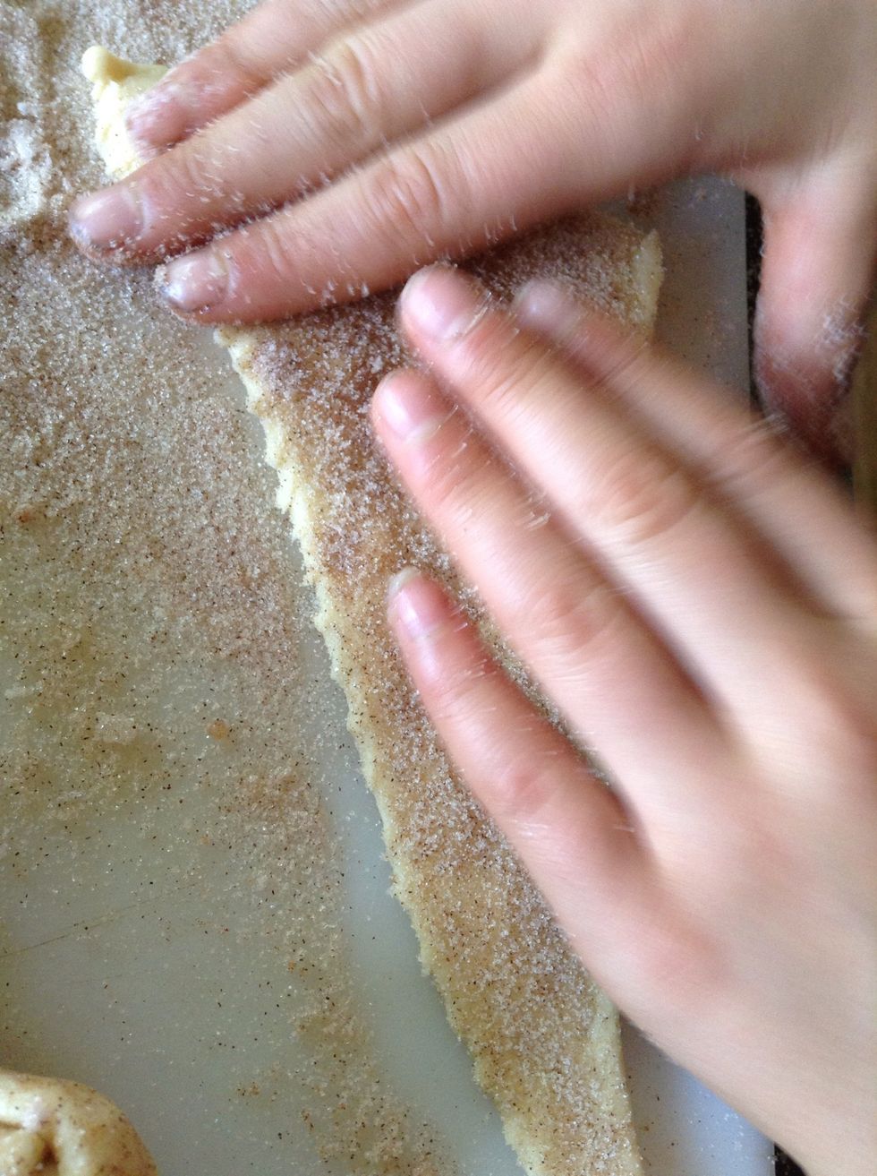 Now brush the butter on the dough, and put some cinnamon and sugar on it. Put the marshmallow on, and roll it.