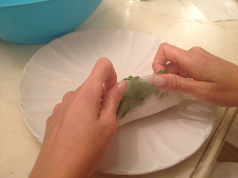 Now, carefully(the rice paper can break easily) peel the bottom up and begin to roll and tuck the roll. Roll halfway...