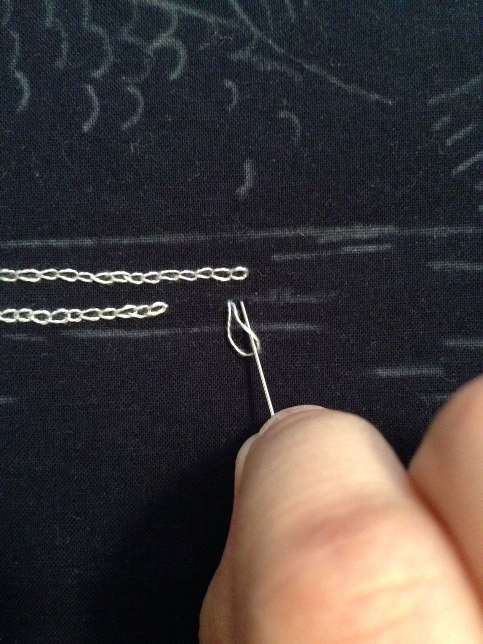 Now coming from the back of the fabric, bring your needle up one stitch length ahead through the fabric and pass it through the loop.