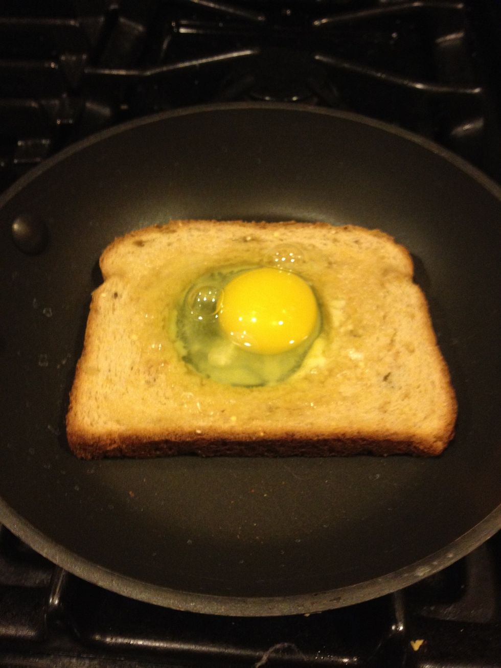 Now crack an egg right into the middle of the hole.