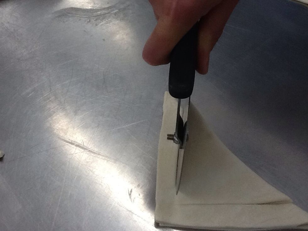 Now cut along the other edge creating a smaller triangle, but do not cut all the way through the pastry.