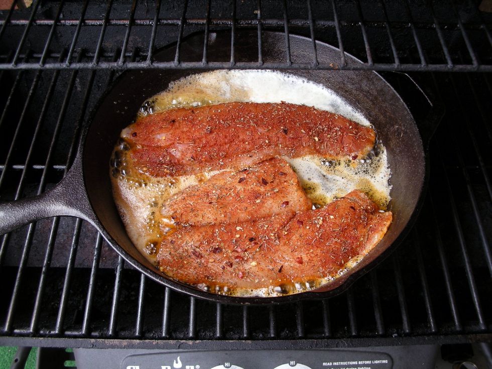 Now drop half the stick of butter into the skillet.   Wait a few seconds for it to brown - that's what "blackens" the fish.   After a few seconds drop in the fillets.