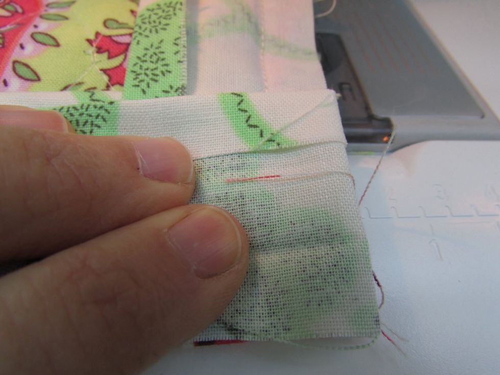 Now fold the same fabric trim piece back over itself to the left, covering the triangle fold, and lining the edges up. Hold it down as you turn the whole thing counter-clockwise to sew the next edge.