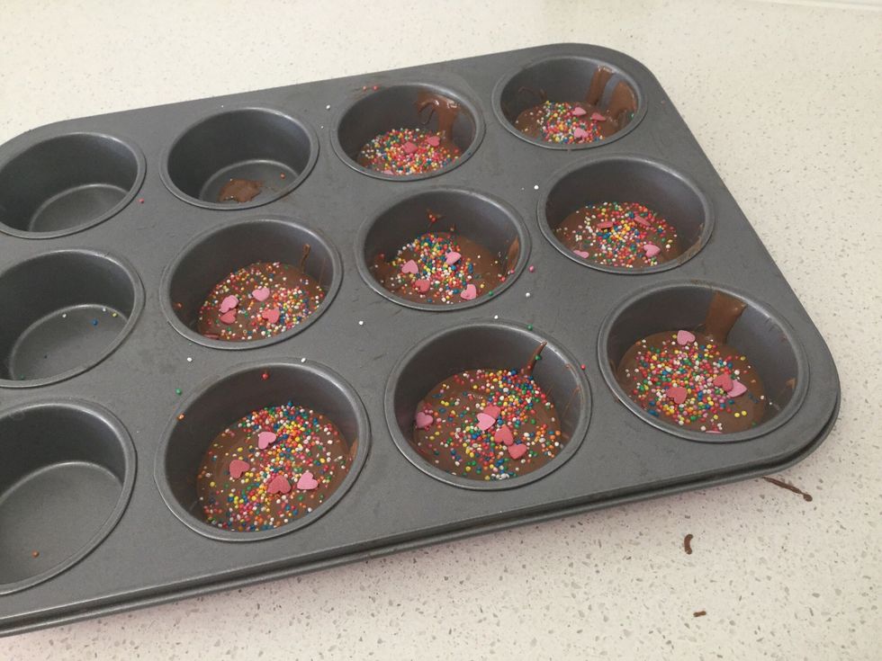 Now for the fun part, pour sprinkles evenly on chocolate freckles. Then add a few sugar hearts.