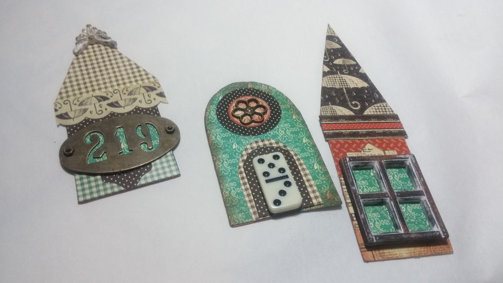 Now for the metal embellishments and mixed media additions. I chose a small domino for a door and a resin window I aged with gilders paste.