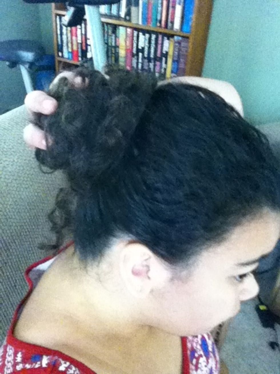 Now get a loose strand and wrap it around the base of your bun a time or two, tucking it in tight with your nail.