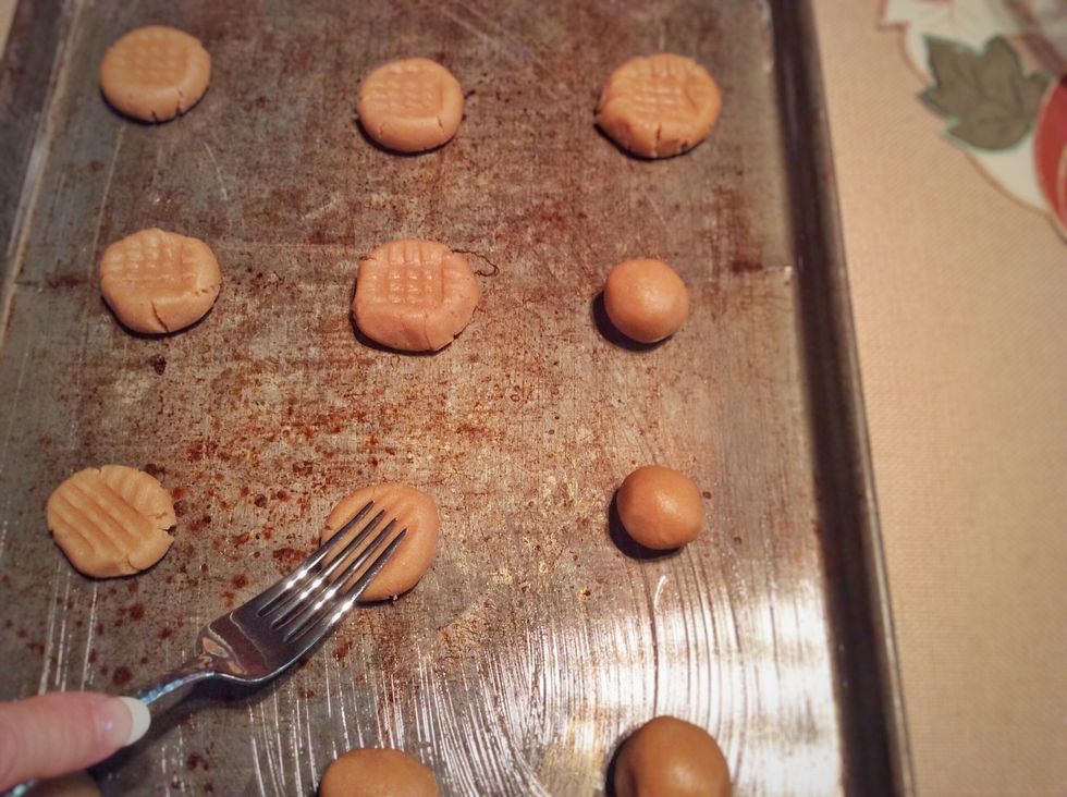 Now, grab a fork and press a fork on the cookies 2 different ways. This flattens the cookies and gives them a nice design.