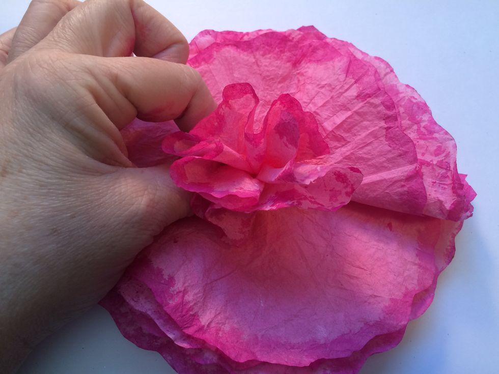 Now...grab the top coffee filter and start pinching it from the center. Scrunch it up between your fingers to create the inside petal. You will do this with each separate filter to form the flower.