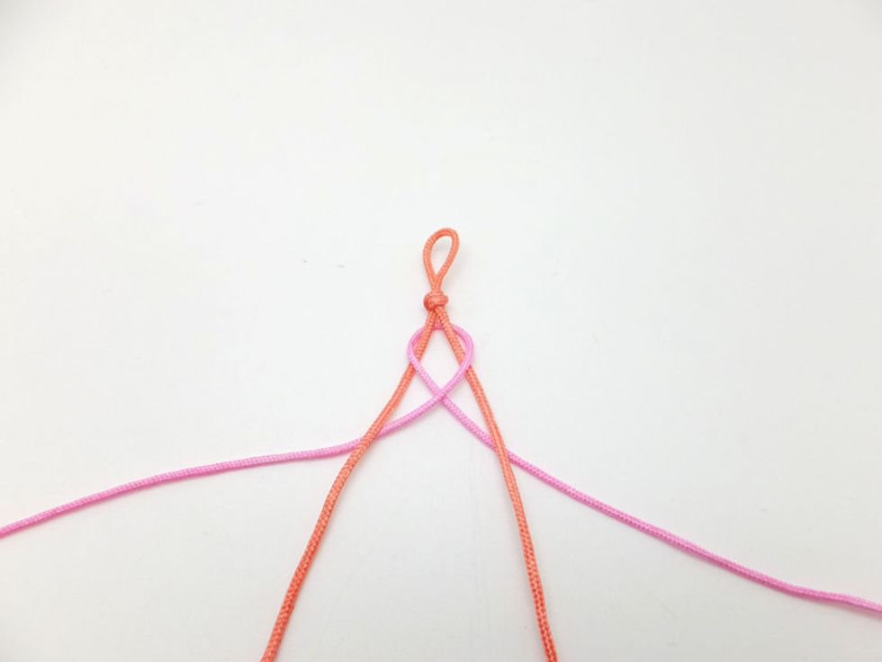 Now, grab the top strand on the right side and weave it over the right orange cord and under the left orange cord.