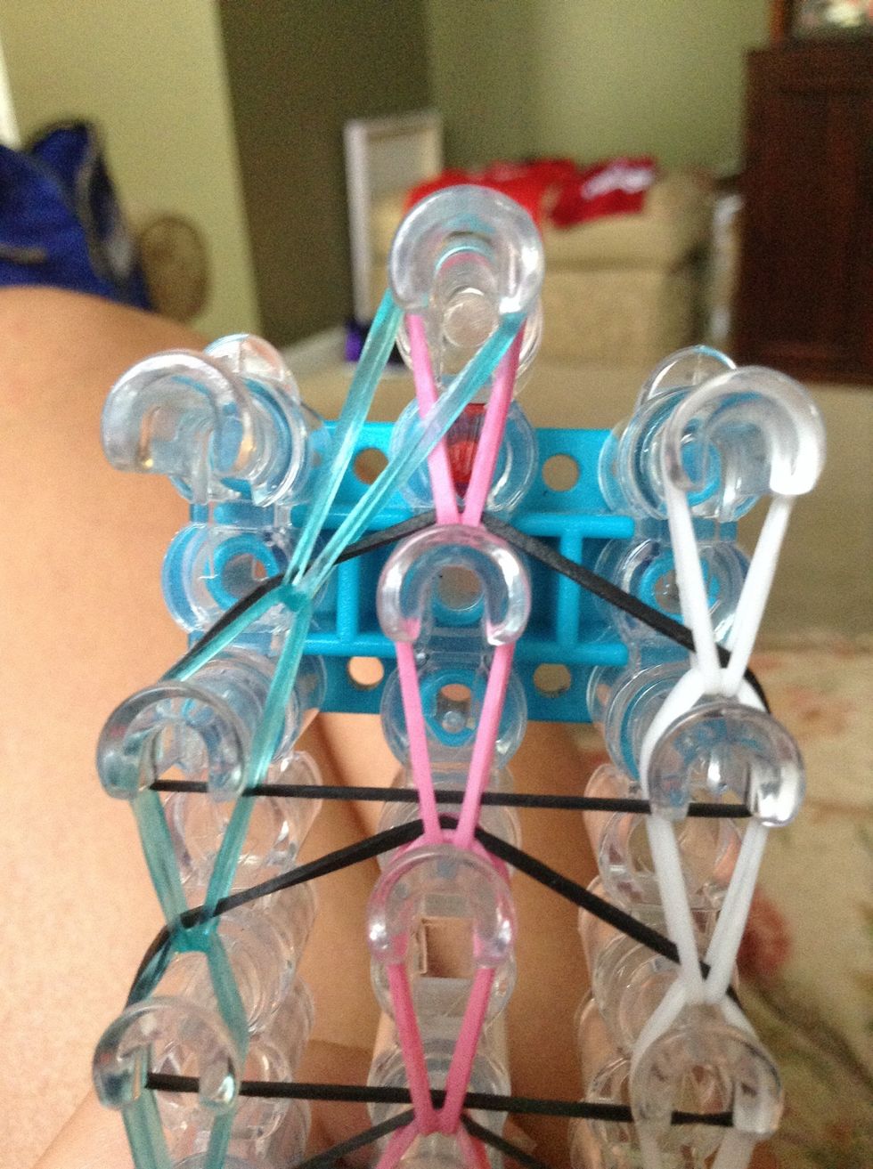 Now hook the top rubber band in the left row to the peg on the right.