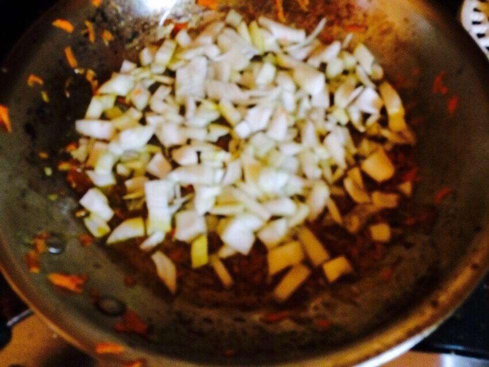 Now I like to add fresh seasoning like onion and garlic. I chop up the onion and place in that same frying pan now with potato and carrot bits.