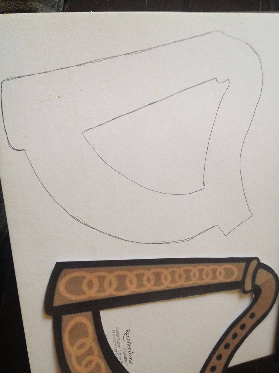 now I'm cutting out the shape of the harp. start by tracing on the back of the gold glitter paper... BUT WAIT... I've made a mistake already, can you catch it??
