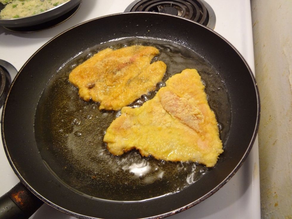 Now in a pan, heat oil and put chicken cutlets in it. Cook two chicken cutlets at a time with 5 mins each side. You'll know they are done when they turn golden brown.