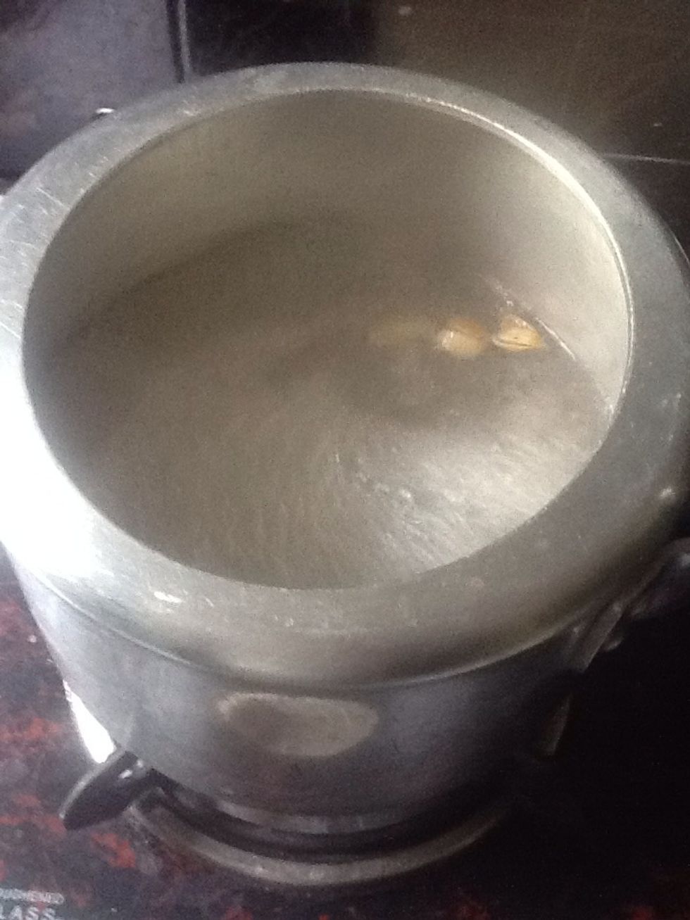 Now in a pressure cooker take a cup of water and heat it with a cup of sugar. To that add 1/2 tbsp cardamom powder.