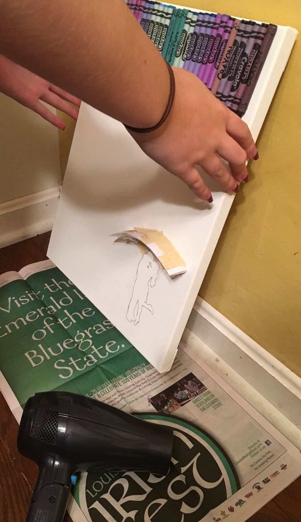 Now it's time to melt. Plug in your hairdryer and sit the canvas up against a wall. Make sure to have newspaper laying underneath. I did mine on the floor to make it easier.