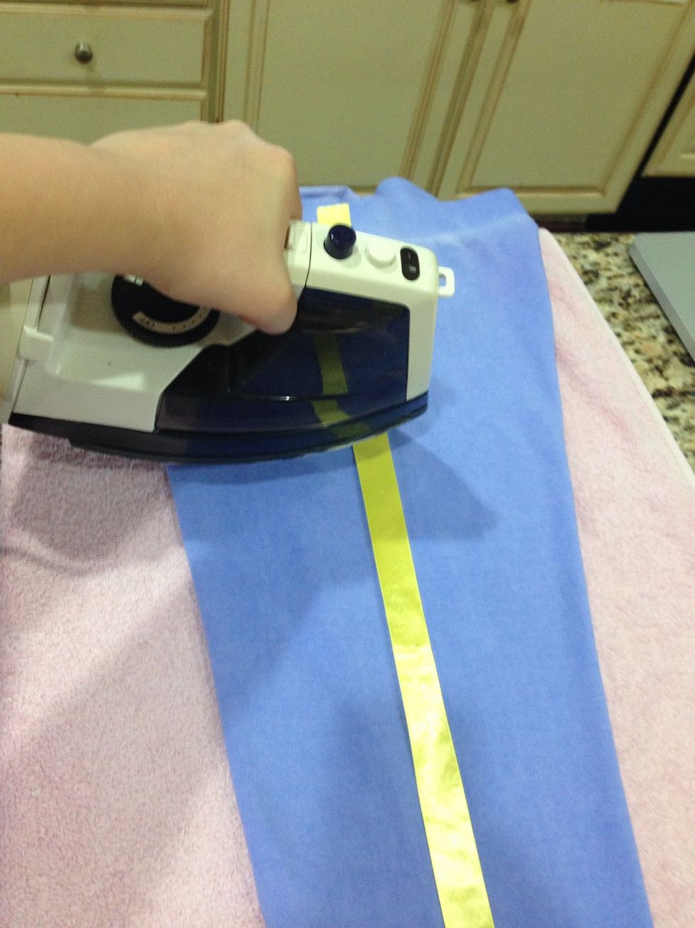 Now lay the ribbon on top of the crease you created. When you are ready press the iron on top of the ribbon. Hold it for about 8 seconds. Repeat this until all the ribbon is fused to the pants.