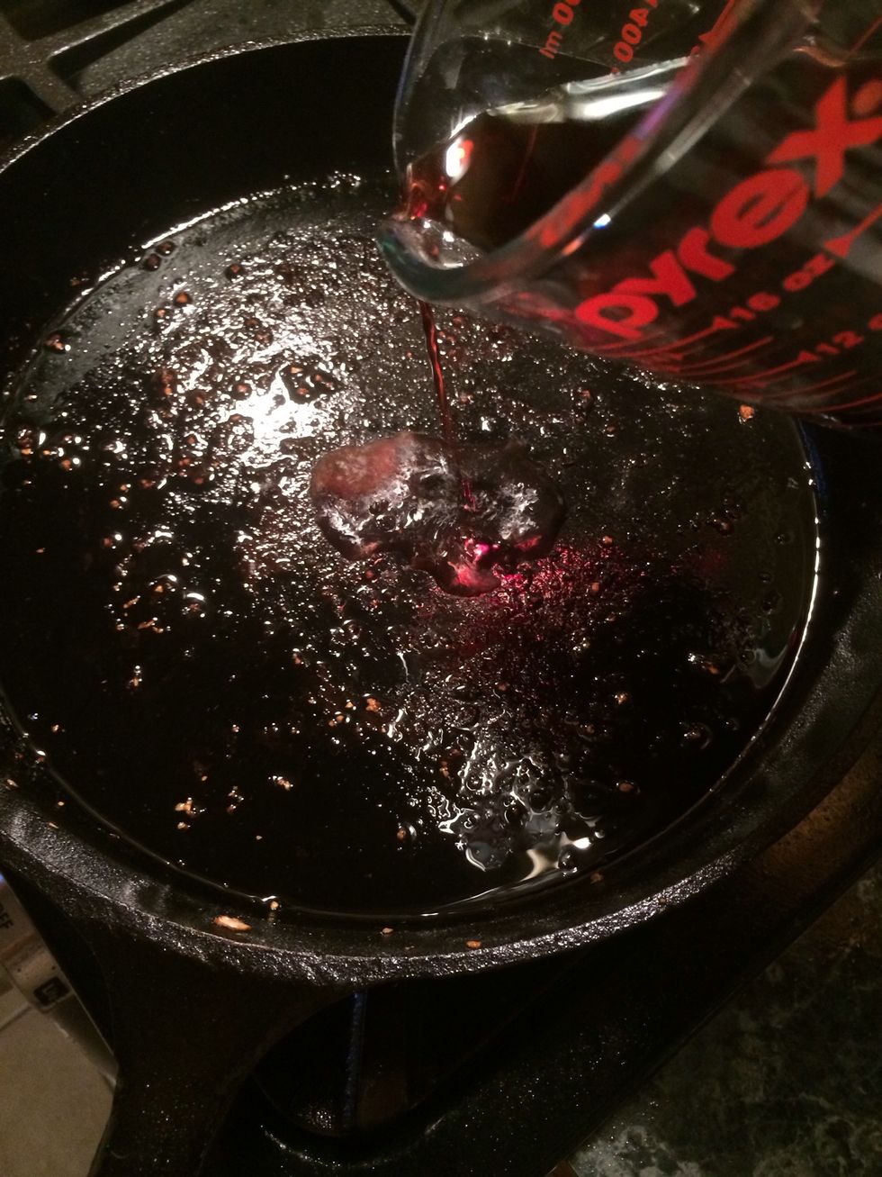 Now let's deglaze the pan with the red wine. Take a spoon and stir the pan mixing in the wine.