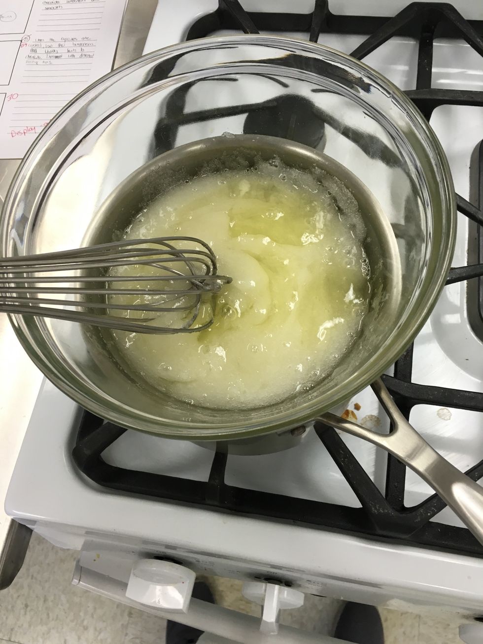 Now let's make the Swiss meringue buttercream. Make a double boiler by heating a saucepan with water and setting a glass bowl on top. Add the egg whites and sugar and heat until it's 140 degrees F.
