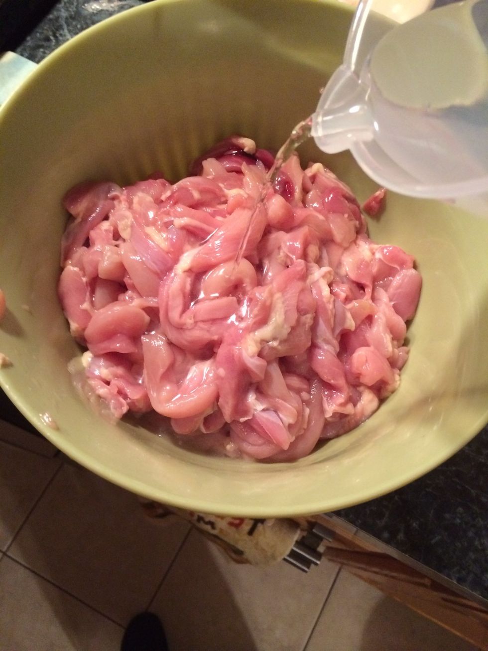 Now let's start the marinade. Add the water to the chicken.
