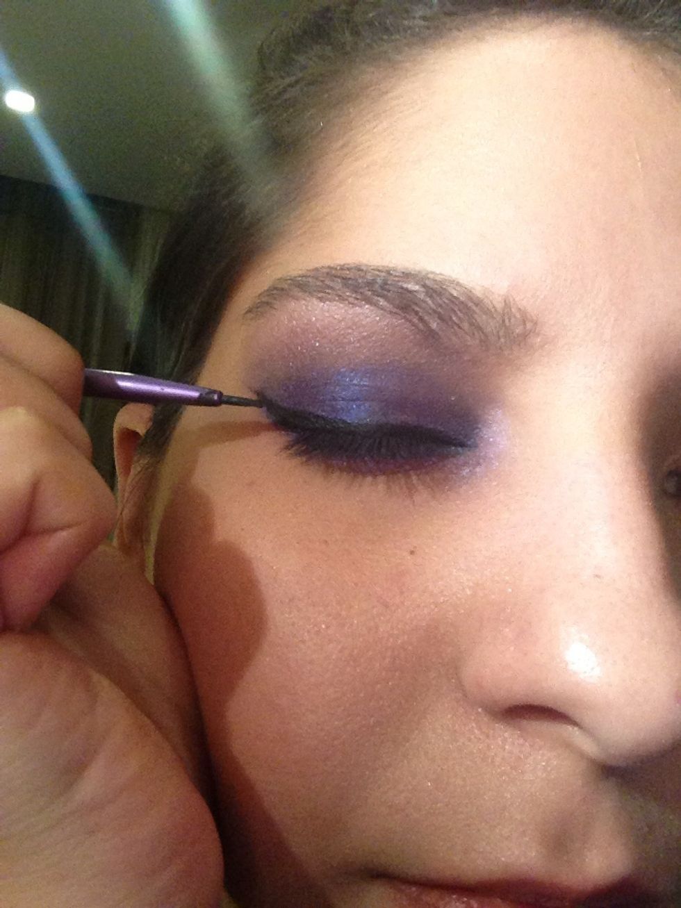 Now line your eyes with a black gel liner, creating a winged shape.